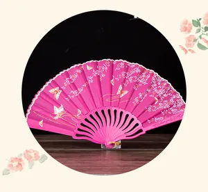 Close-up of pink folding fan with butterfly and floral patterns on a wooden surface