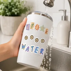Primer plano de pegatinas de letras DIY de colores en un vaso blanco con agua
