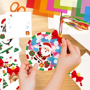 Vista detallada de manos creando un adorno navideño de Papá Noel DIY con papel y pegatinas
