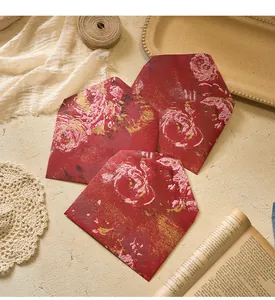 Vintage red floral envelopes displayed on a rustic desk with artistic props for letters