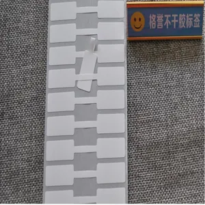 Close-up detail of blank white dumbbell-shaped jewelry price tags on a roll for labeling