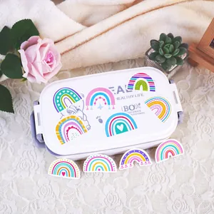 Close-up of colorful cartoon rainbow stickers applied to a white lunch box surface.