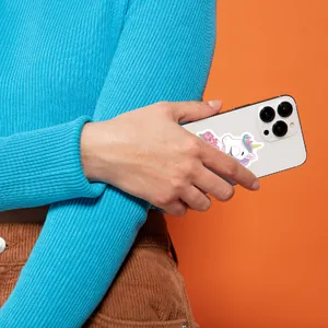 Detailansicht eines niedlichen Einhorn-Aufklebers auf einem Smartphone in der Hand.
