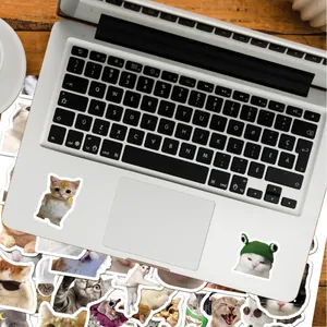 Gros plan d'autocollants de chats mignons décorant un ordinateur portable argenté.
