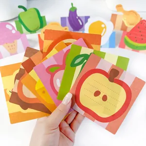 Close-up detail of cute fruit-themed sticky notes held in hand showing a red apple design