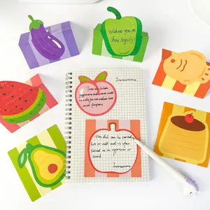 Top view of various fruit and food sticky notes placed around a notebook and a unicorn pen