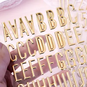Close-up macro detail of 3D metallic gold alphabet stickers on transparent sheet background