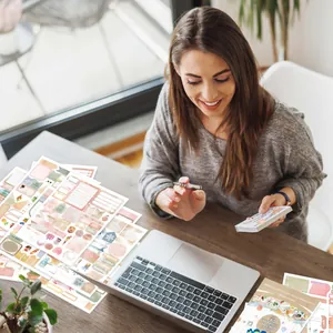 Mujer usa pegatinas de acuarela vintage en su escritorio para organizar su diario