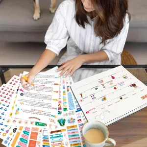 Primer plano de una mujer usando pegatinas de colores en un cuaderno de agenda para diario.
