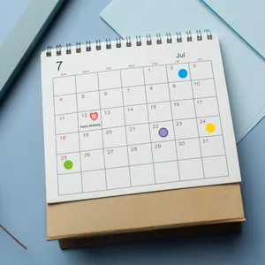 Gekleurde ronde puntstickers gebruikt als datummarkering op een papieren kalender