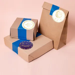 Gold foil Ramadan moon stickers applied on brown paper gift boxes with blue ribbon