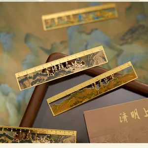 Close-up of gold metal bookmarks with hollowed Chinese landscape and character designs.