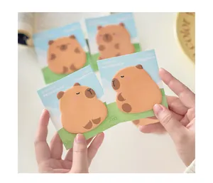 Simpatici foglietti adesivi a forma di capibara per il journaling tenuti nelle mani