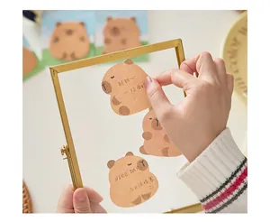 Primo piano di simpatici post-it a forma di capibara su una cornice di vetro per agenda.