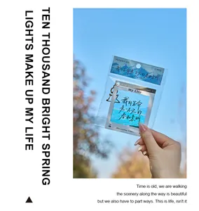 Creative PET bookmark keychain held against a scenic blue sky background