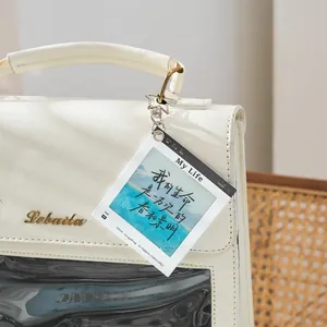 Minimalist PET slide keychain hanging on a white backpack with inspirational quote print.