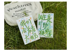 Gros plan de cartes postales inspirantes avec calligraphie chinoise sur l'herbe verte.