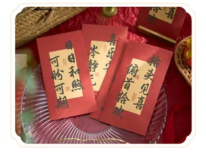 Gros plan d'enveloppes rouges chinoises avec vœux en calligraphie sur papier doré.
