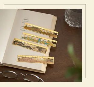 Close-up detail of four golden metal landscape bookmarks placed on an open literary book