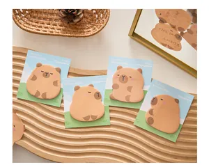 Quattro confezioni di simpatici post-it di capibara disposti su un vassoio di legno.