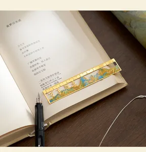 Close-up of a golden Chinese style landscape metal ruler bookmark placed on an open book