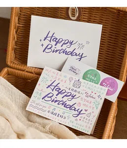 Artistic birthday greeting card and envelope set displayed in a rustic wicker basket