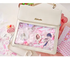 Close-up of cream ita bag clear window filled with pink lace ribbons and anime badges