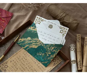 Gros plan d'une enveloppe bronze verte rétro et de papier à lettres sur plateau en bois.