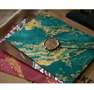 Gros plan d'enveloppes rétro texturées marbre doré avec un sceau de cire en bronze.
