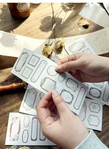 Detail of hands peeling a vintage style decorative frame sticker for scrapbooking