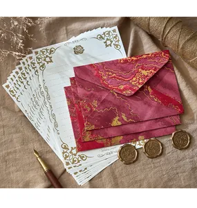 Détail d'un ensemble de papeterie vintage avec enveloppes marbrées rouges et dorées.