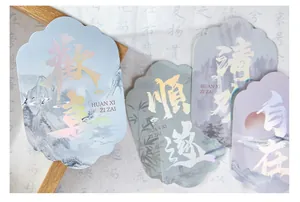 Nahaufnahme von Deko-Karten mit holografischer Kalligraphie und Landschaftskunst.