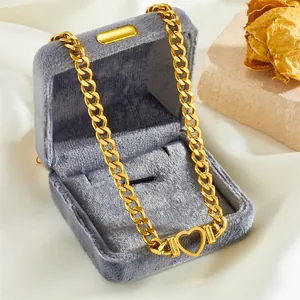 Collier chaîne cubaine en or avec pendentif cœur ajouré dans un écrin en velours gris
