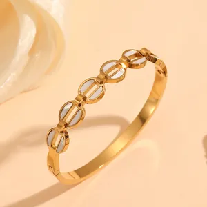 Macro view of gold stainless steel bangle featuring circular geometric white shell inlay