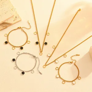 Close-up detail of stainless steel flower charm necklaces and bracelets on beige background