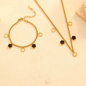 Detailed view of gold flower necklace and bracelet set with black enamel accents