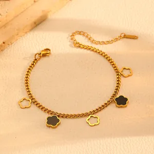 Close-up of a gold stainless steel bracelet with black and hollow flower charms
