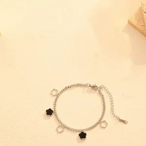 Detailed view of silver stainless steel bracelet featuring black and hollow flower charms.
