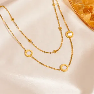 Macro detail of a double-layered gold-tone chain necklace with Roman numeral pendants.
