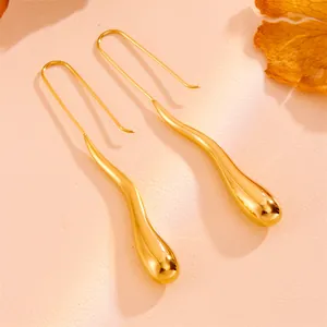 Macro view of gold teardrop earrings with elegant curved hooks and polished finish