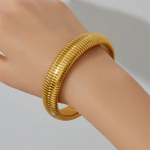 Close-up of gold stainless steel elastic striped Tubogas style bangle worn on the wrist.