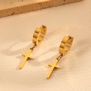 Macro view of gold-plated titanium steel cross hoop earrings on elegant textured background.