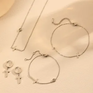 Macro view of titanium steel jewelry set featuring minimalist cross pendants and small gems