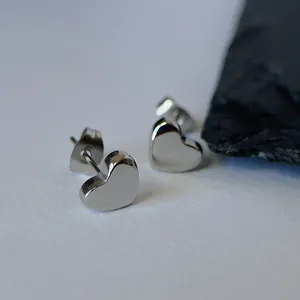 Close-up of silver heart-shaped stud earrings in titanium steel with polished finish.