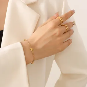 Elegant minimalist gold heart charm bracelet and chunky chain rings worn by a model