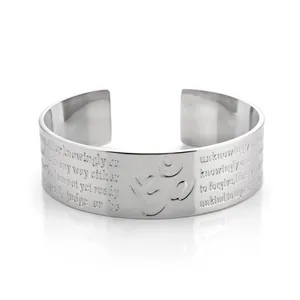 Close-up of a silver stainless steel cuff bracelet with Om symbol and engraved spiritual text