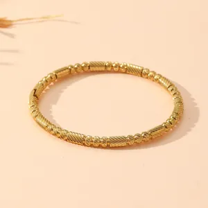 Vue détaillée d'un jonc vintage en acier inoxydable doré avec perles mates et texture