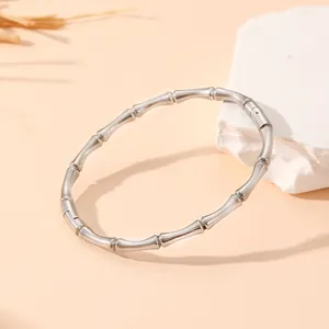 Détail d'un bracelet jonc en acier inoxydable à motif bambou argenté sur pierre.