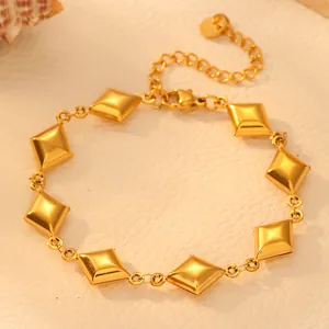 Detailed macro view of golden titanium steel geometric rhombus bracelet on cream surface