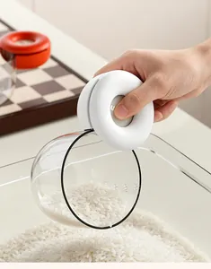 Vista detallada de un mango ergonómico blanco en una cuchara medidora de arroz transparente
